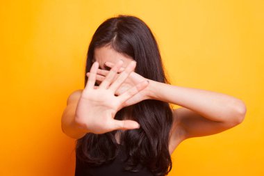 Genç Asyalı kadın yüzünü Sarı zemin üzerine gizle