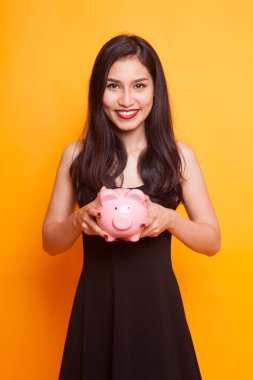 Genç Asyalı kadın Sarı zemin üzerine bir domuz para banka ile