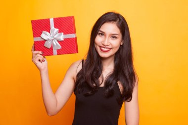 Sarı arka plan üzerinde bir hediye kutusu ile genç Asyalı kadın