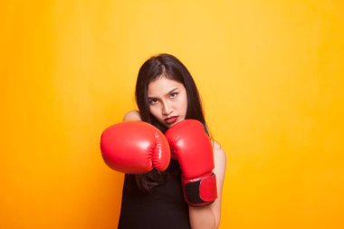 Sarı zemin üzerine kırmızı boks eldivenli genç Asyalı kadın