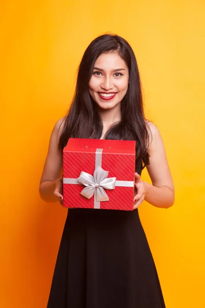 亚洲女人竖起了一个黄色背景的礼品盒 — 图库照片