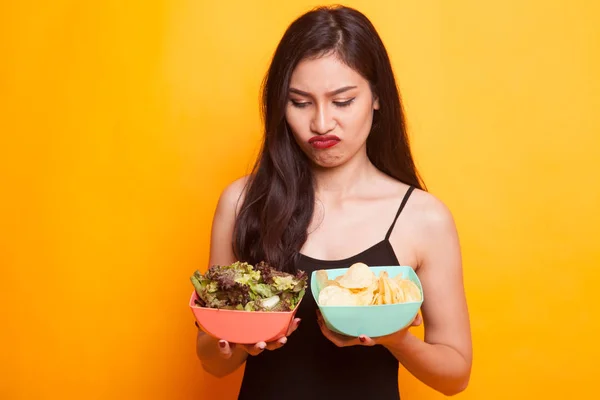 Junge Asiatin Mit Kartoffelchips Und Salat Auf Gelbem Hintergrund — Stockfoto