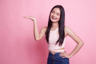 Pembe arka planda eli olan genç bir Asyalı kadın var.