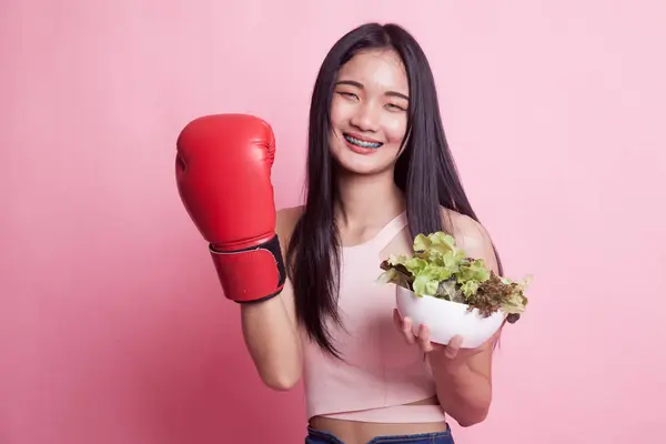 年轻亚洲妇女与拳击手套和沙拉在粉红色背景 — 图库照片