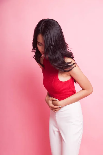 Young Asian woman got stomachache on pink background