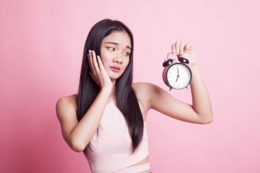 Genç Asyalı kadın ile bir saat pembe bir arka plan üzerinde vurguladı