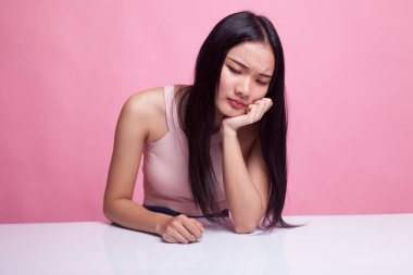 Asyalı kız pembe arka planda sıkılıyor.