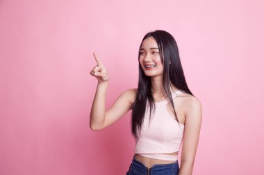 Asyalı kadın pembe arka planda parmaklarıyla ekrana dokunuyor.