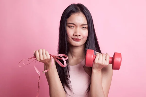 精疲力尽的亚洲妇女用哑铃和测量磁带在粉红色背景 — 图库照片