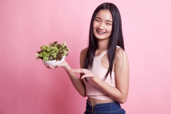 Healthy Asian woman with salad on pink background