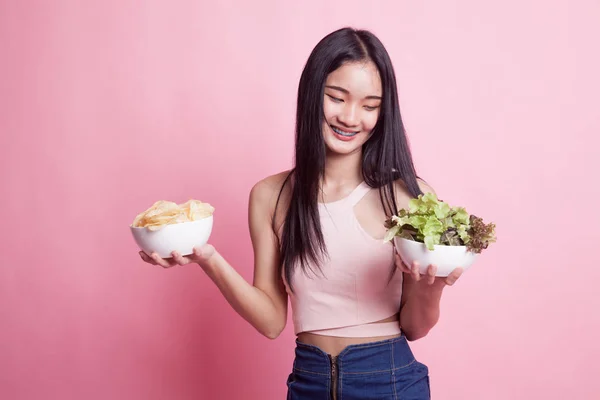 年轻的亚洲女人 有薯片和粉色背景的沙拉 — 图库照片