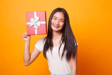 Parlak sarı zemin üzerine bir hediye kutusu ile Genç Asyalı kadın