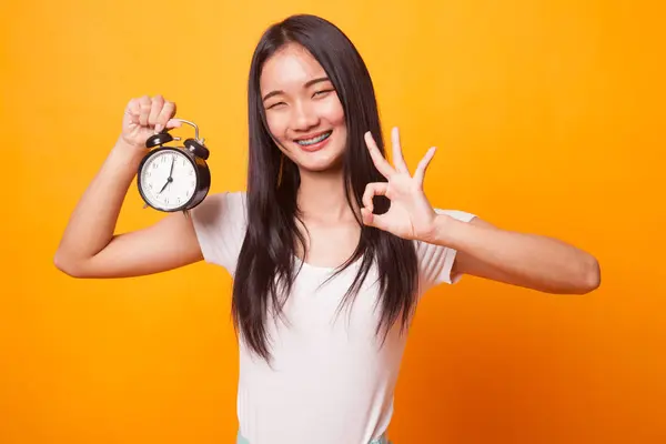 Joven Mujer Asiática Muestran Con Reloj Sobre Fondo Amarillo Brillante —  Fotos de Stock