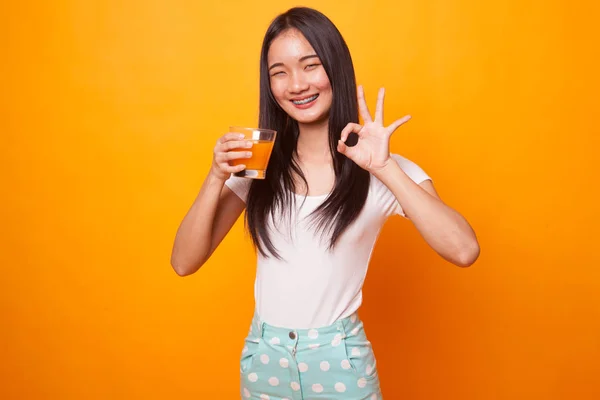Joven Mujer Asiática Beber Zumo Naranja Mostrar Signo Sobre Fondo — Foto de Stock