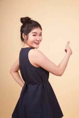 Genç Asyalı kadın bej arka planda baş parmağını kaldırdı