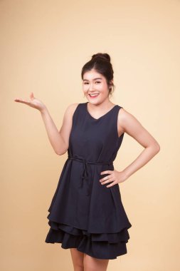 Genç Asyalı kadın elini bej arka planda tutuyor.