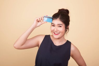 Genç Asyalı kadın bej arka planda boş bir kartla düşünüyor.