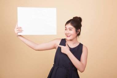 Genç Asyalı kadın bej arka planda boş bir işaret gösteriyor.