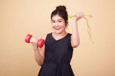 Dambıl ve bej renkli arka plan üzerinde ölçüm bandı ile sağlıklı Asyalı kadın