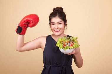 Genç Asyalı kadın ile boks eldiven ve salata bej renkli arka plan üzerinde