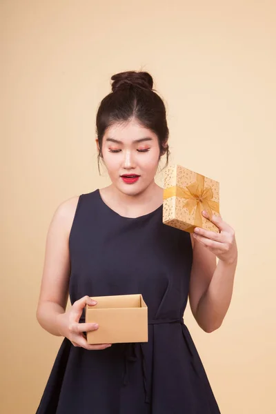 年轻的亚洲女人打开一个米色背景的礼品盒 — 图库照片