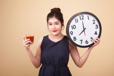 Domates suyu ve bej renkli arka plan üzerinde saat ile genç Asyalı kadın