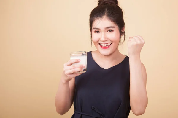 Healthy Asian woman drinking a glass of milk  on beige background