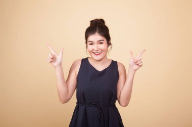 Genç Asyalı kadın bej arka planda sağı solu işaret ediyor