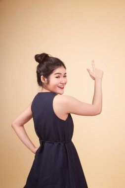 Asyalı bir kadın bej arka planda parmağıyla ekrana dokunuyor.