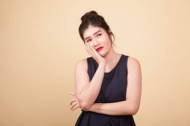 Güzel genç Asyalı kadın bej arka planda sıkılır.