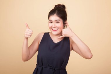 Genç Asyalı kadın bej arka planda telefon jesti ile gösteriyi onayladı