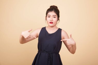 Genç Asyalı kadın kendini işaret ederek neden bej arka planda olduğumu soruyor.