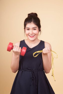 Dambıl ve bej renkli arka plan üzerinde ölçüm bandı ile sağlıklı Asyalı kadın