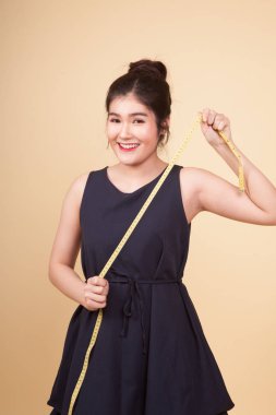 Teyp bej renkli arka plan üzerinde ölçüm ile genç Asyalı kadın