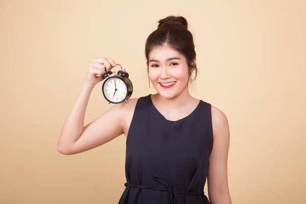 Young Asian woman with a clock  on beige background