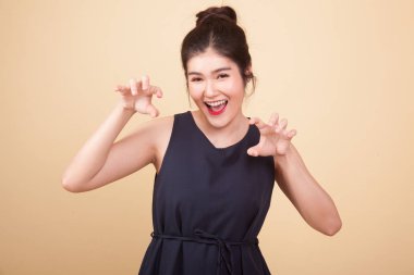 Bej renkli arka plan üzerinde ürkütücü el hareketi ile genç Asyalı kadın