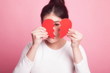 Pembe arka planda kalbi kırık güzel bir Asyalı kadın.