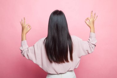 Asyalı kadının arka plan görüntüsü pembe arka planda çift tamam el işareti