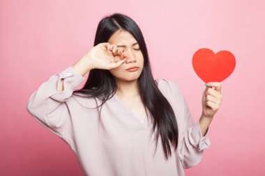 Asyalı kadın üzgün ve pembe bir arka plan üzerinde kırmızı kalpli cry