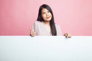 Genç Asyalı kadın pembe arka planda boş işareti olan baş parmağını gösterdi.