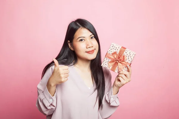 若いアジア女性のピンクの背景にギフト ボックスと親指 — ストック写真