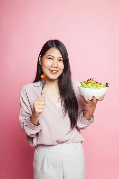 Healthy Asian woman with salad on pink background