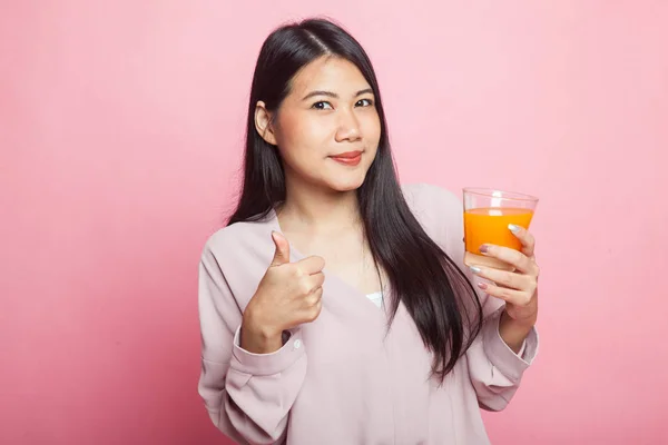 若いアジア女性の親指ピンク背景に飲むオレンジ ジュース — ストック写真