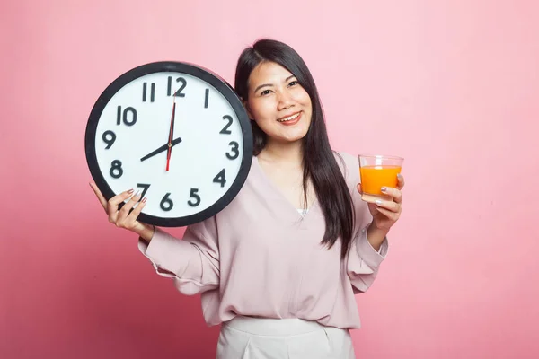 亚洲妇女与时钟喝橙汁在粉红色背景 — 图库照片