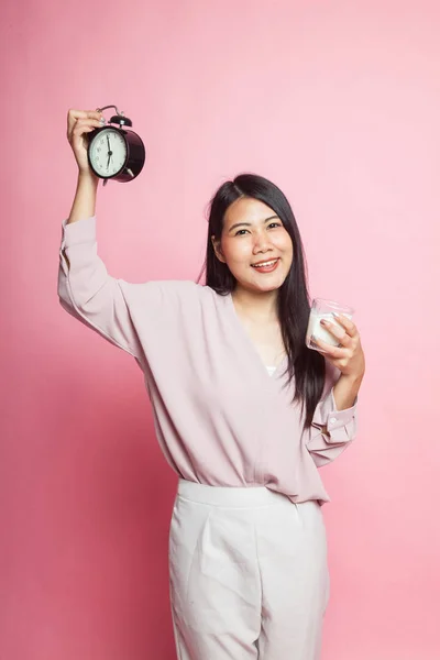 アジアの女性の健康なミルクのコップ ピンク背景に時計を保持します — ストック写真