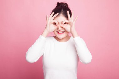 Asyalı kadın yapmak komik Çift Ok işareti olarak pembe bir arka plan üzerinde gözlük