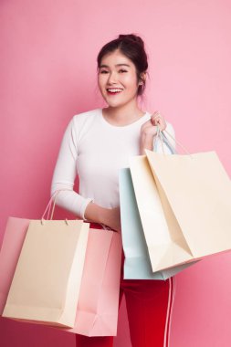 Genç Asyalı kadın pembe arka planda alışveriş çantasıyla mutlu.