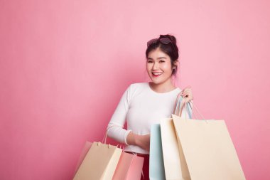 Genç Asyalı kadın pembe arka planda alışveriş çantasıyla mutlu.