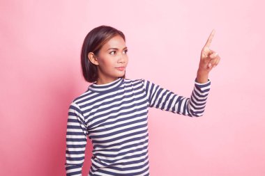 Asyalı kadın pembe arka planda parmaklarıyla ekrana dokunuyor.