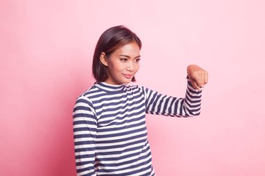 Güzel genç Asyalı kadın pembe arka plandaki boşluğu işaret ediyor.